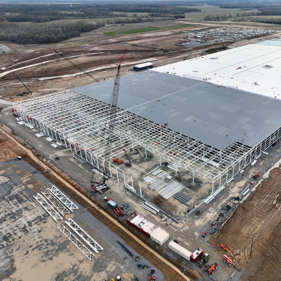 Ford BlueOval City in Tennessee under construction - man in construction uniform on lift using metal grinder on beams