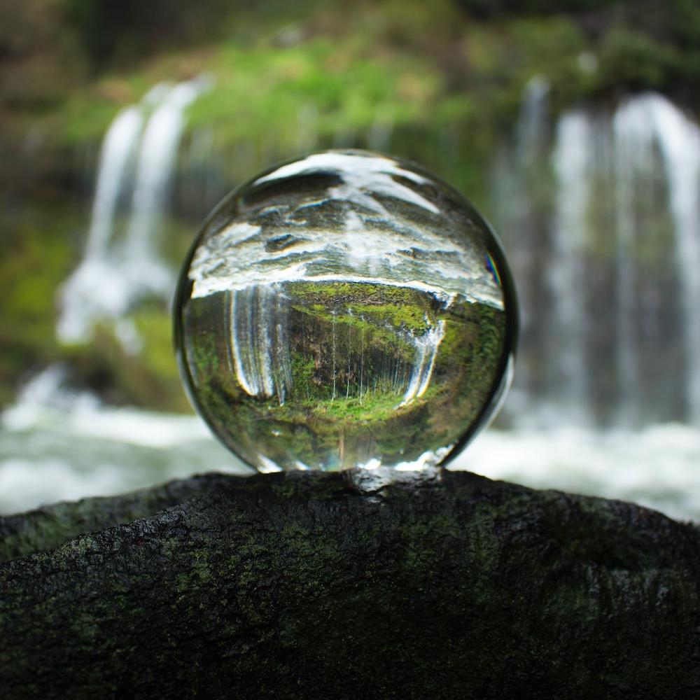 Glass ball reflecting forest and waterfall - Water Stewardship - water stewards - sustainability