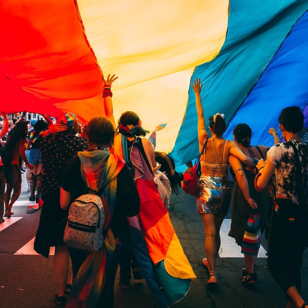 LGBTQ+ pride parade - people holding rainbow banner