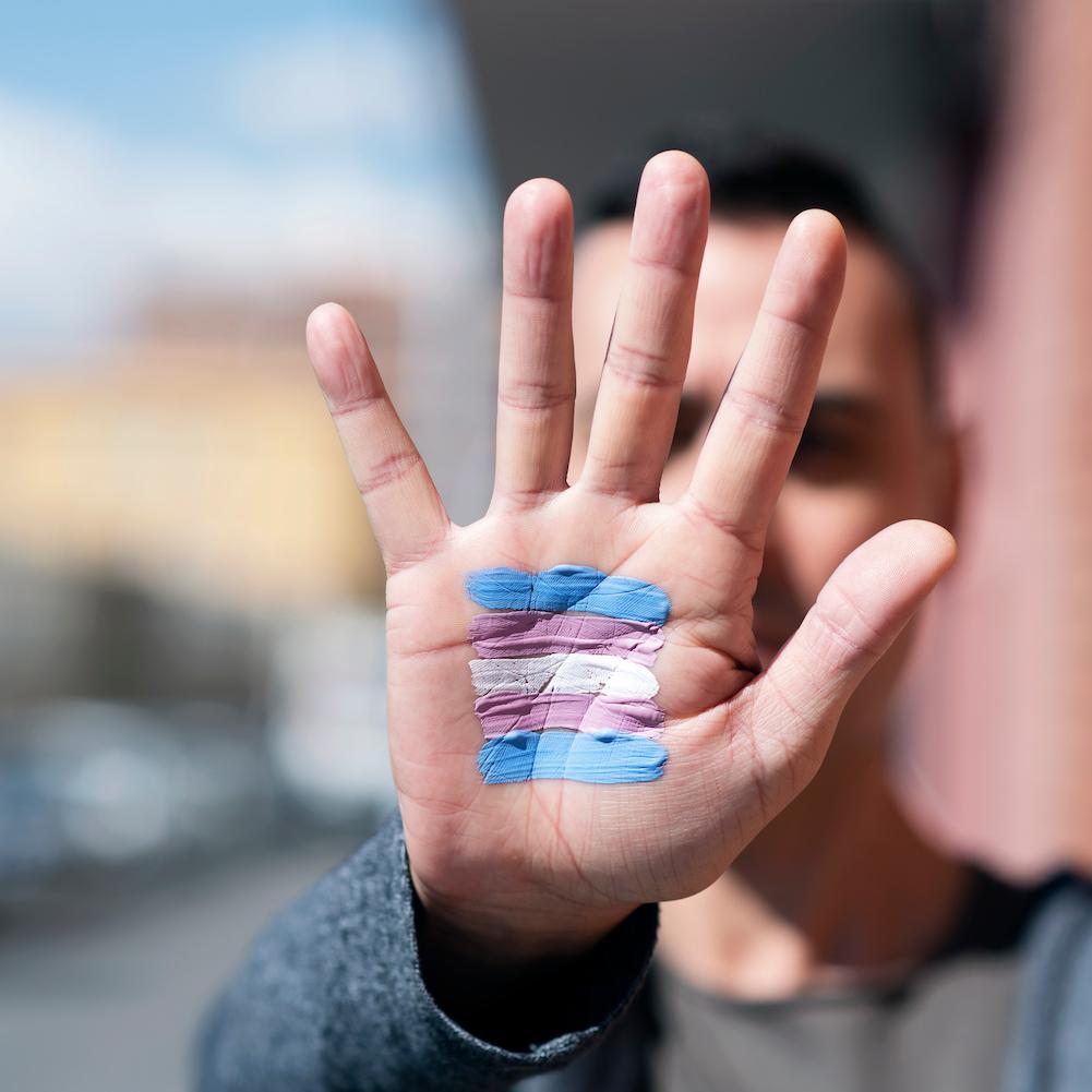 Man with transgender flag painted on the palm of his hand - transgender rights - transitioning