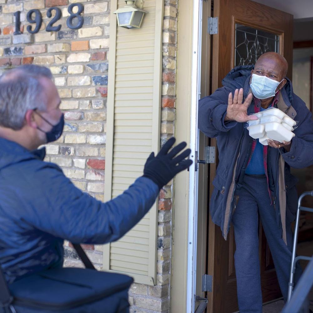 Meals on Wheels volunteer delivers food to a senior at his home
