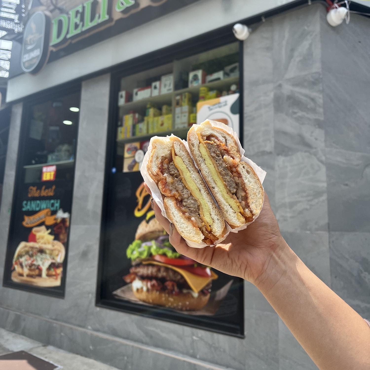 Person holding Plantega plant-based sandwich in front of corner store