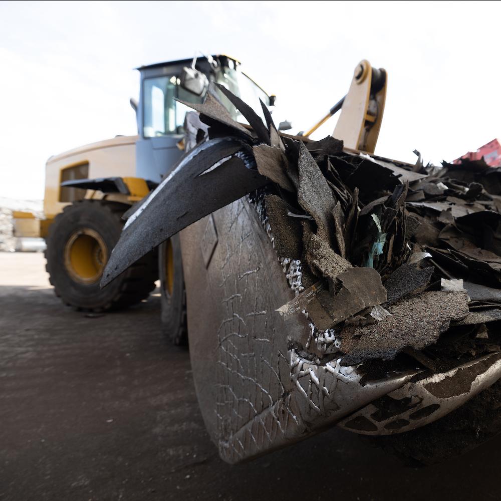 single recycling - backhoe carrying shingle waste for recycling