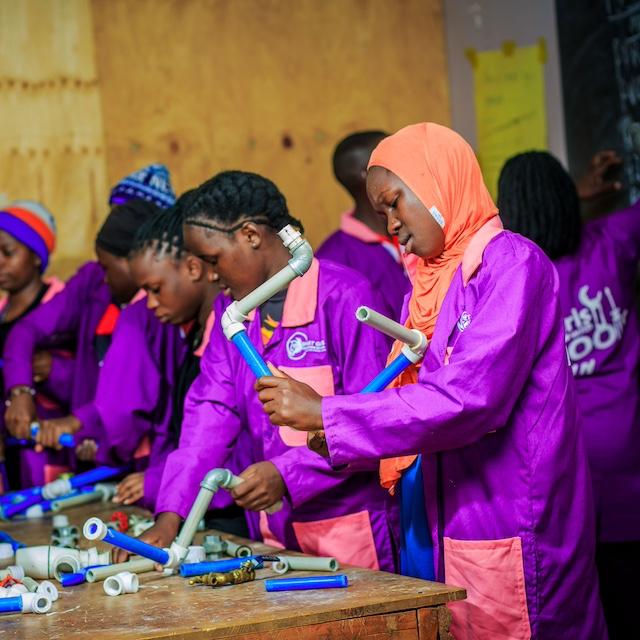 Smart Girls Uganda participants working with piping. 