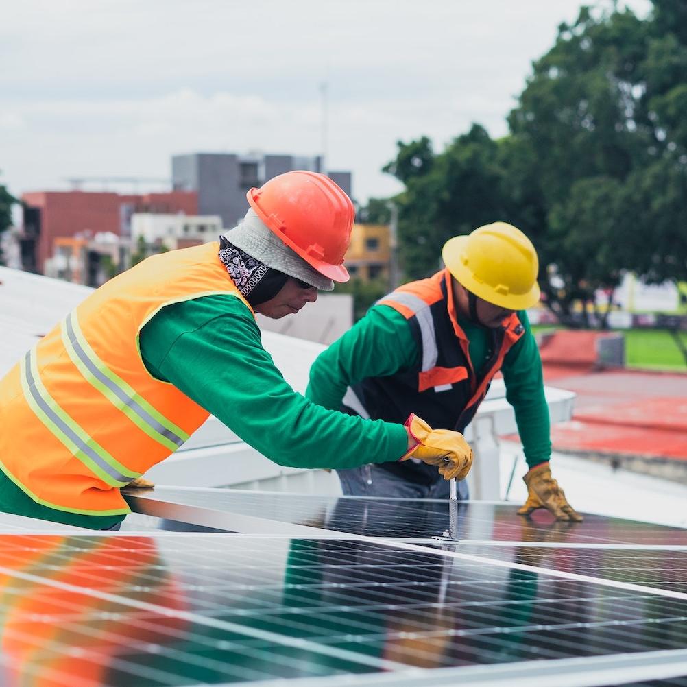 Solar power installers work on roof - clean energy jobs