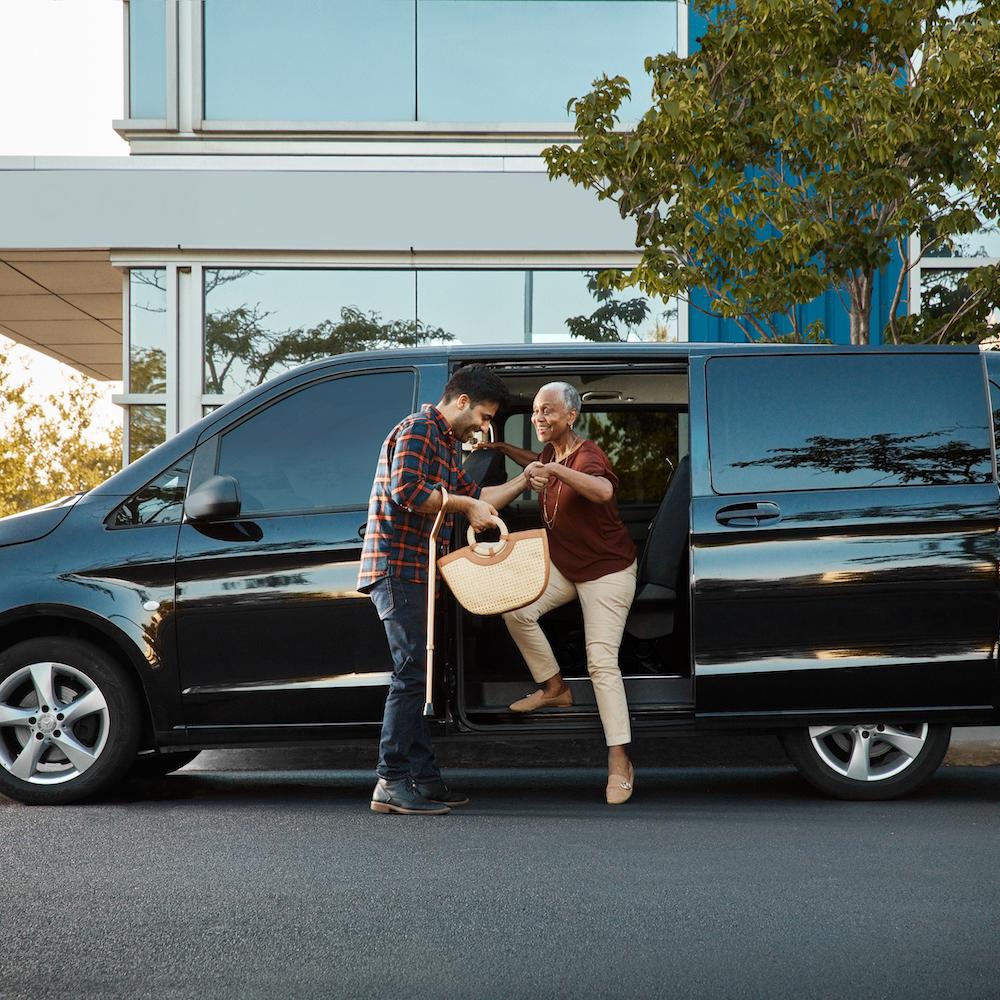 A man helps a woman exit a vehicle. 