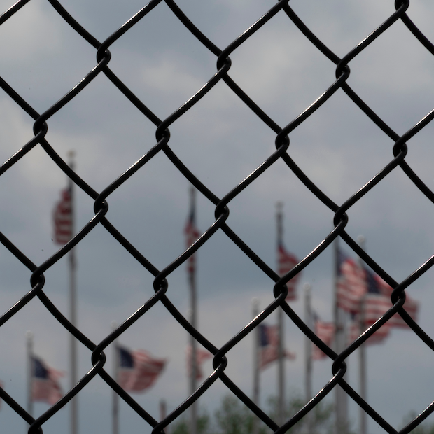 Waving American flags behind fence grid — prisons and prison risk in the US