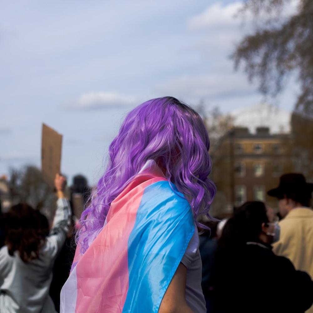 Woman with purple hair at protest wearing transgender flag