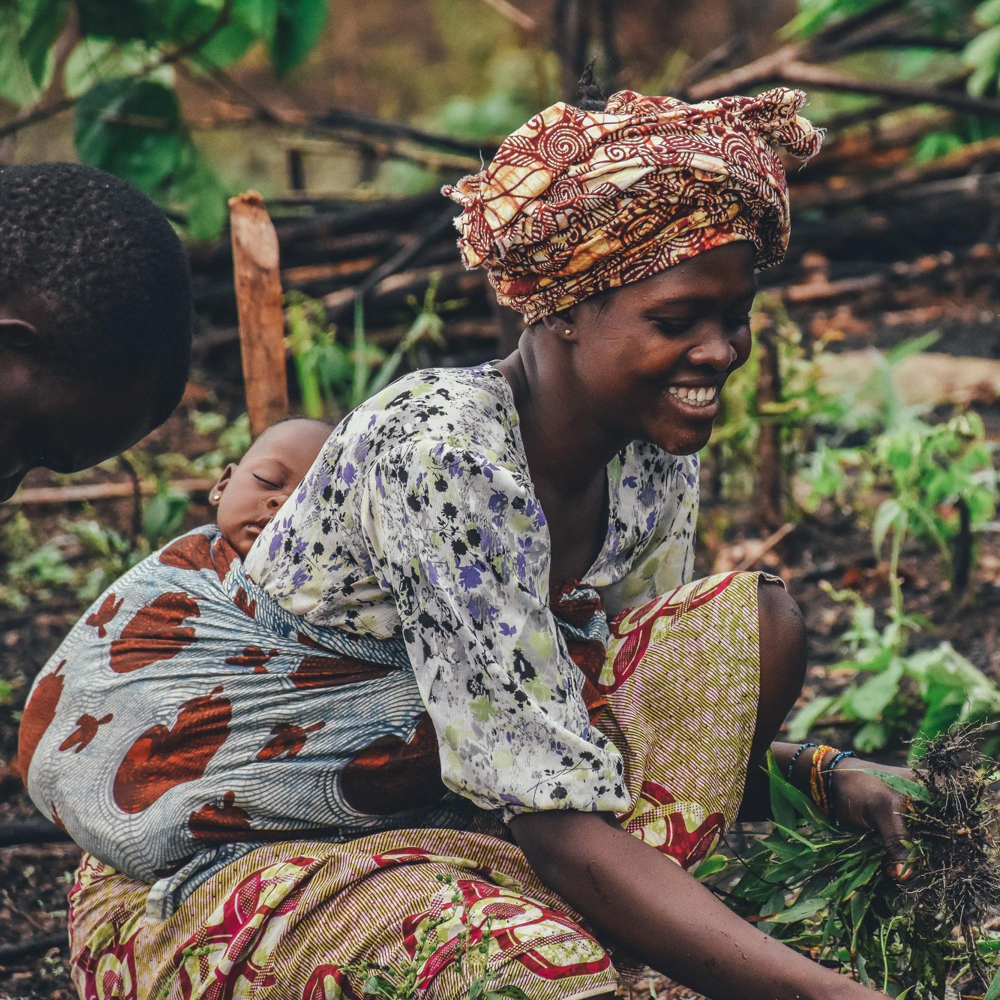 sustainable food systems - woman holding her baby while farming
