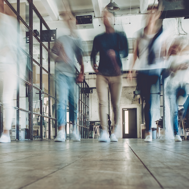 blurred outlines of people walking in the office