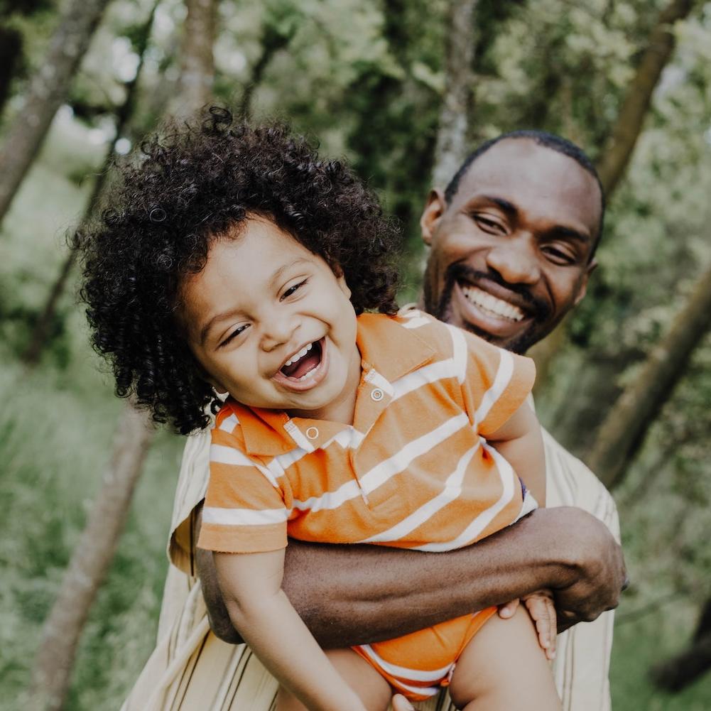 child laughing in fathers arms outdoors