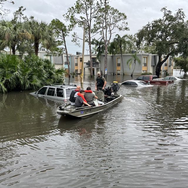A Florida Fish and Wildlife Conservation Commission officer uses a boat to help people get out of a flooded area — climate resilience