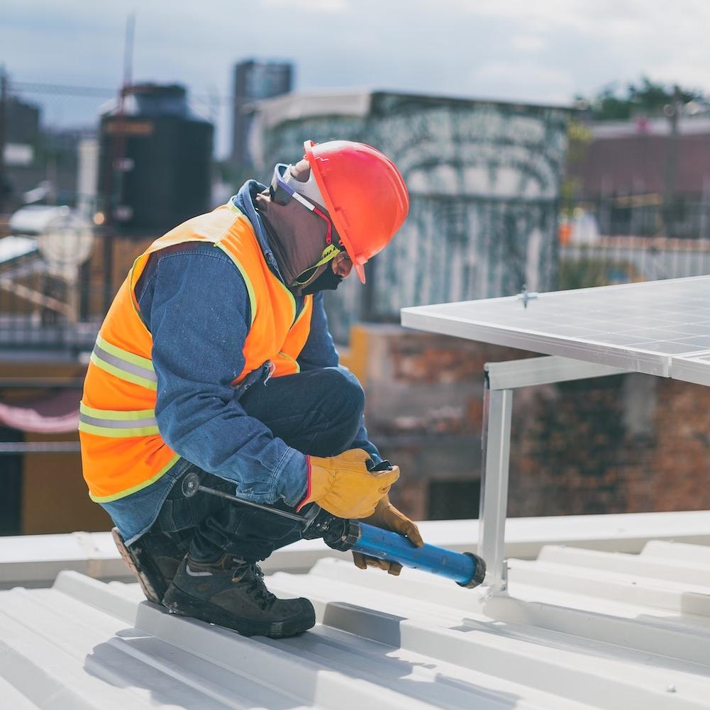 community solar - installer putting solar panels on rooftop in the city