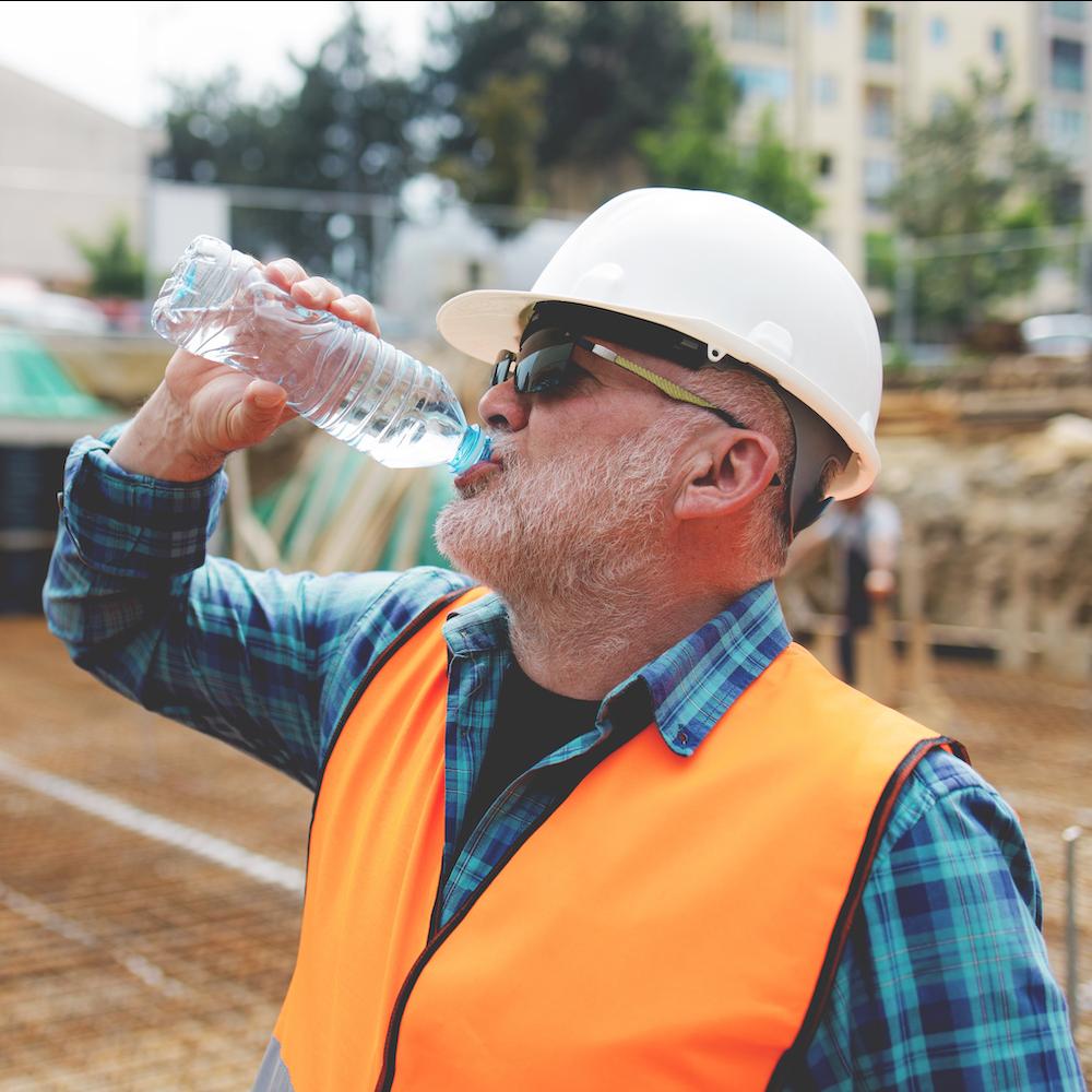 construction worker taking a water break while working outside on a hot day - preventing heat-related illness at work