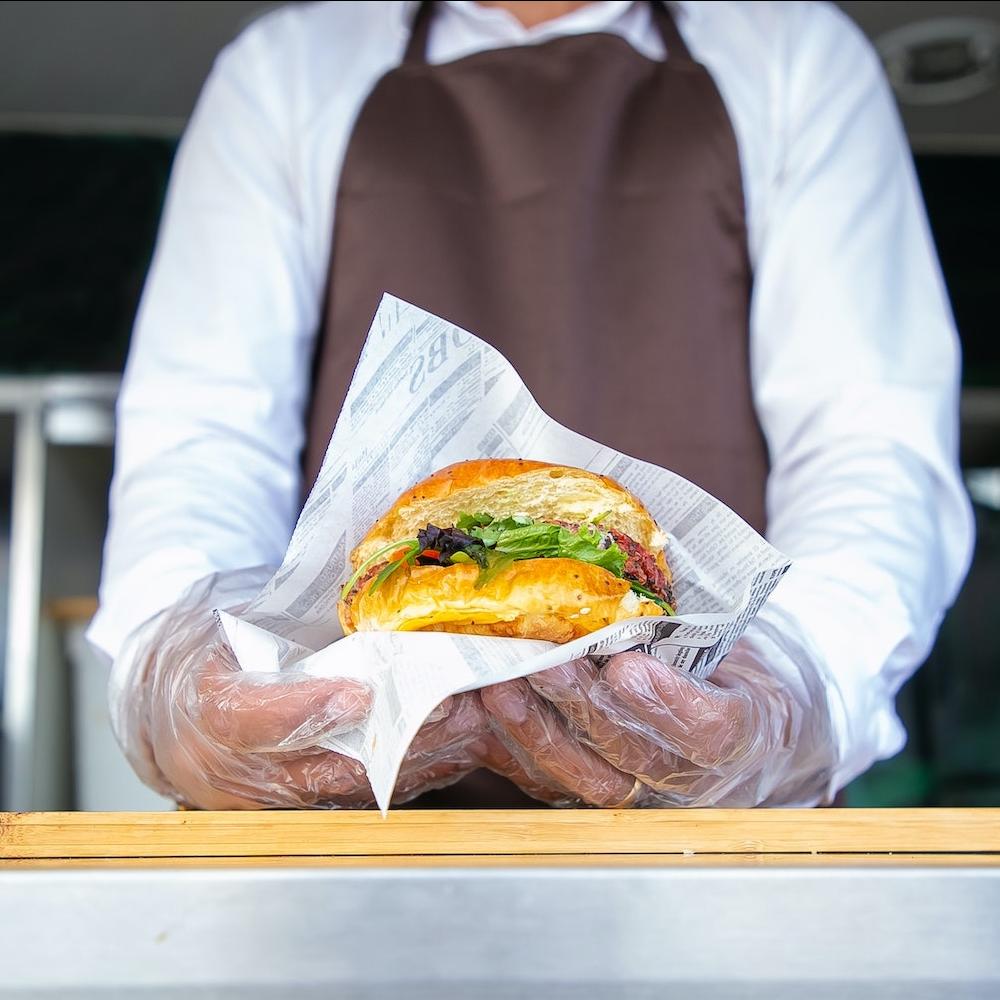 food cart owner holding burger in a wrapper