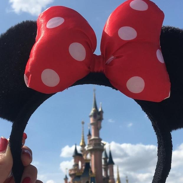 Disney World — woman holds Minnie Mouse headband over magic castle