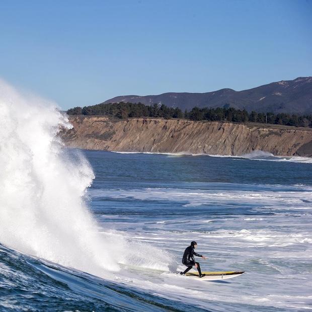 A person surfs in a Patagonia wetsuit at Half Moon Bay in California.