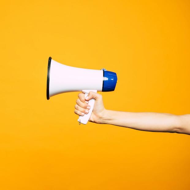 hand holding megaphone against yellow background - the top ESG issues brands should speak out on in 2024