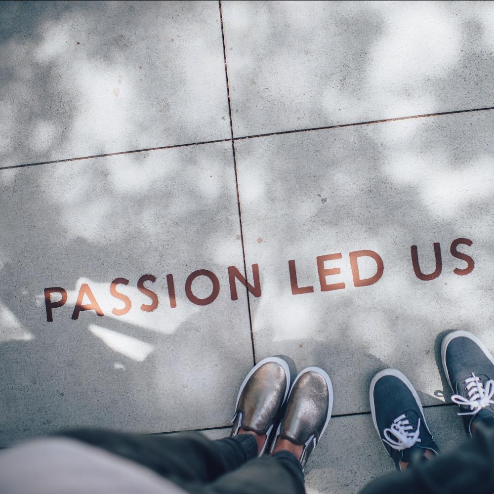 A photo looking down at two pairs of shoes and the words "Passion Led Us".