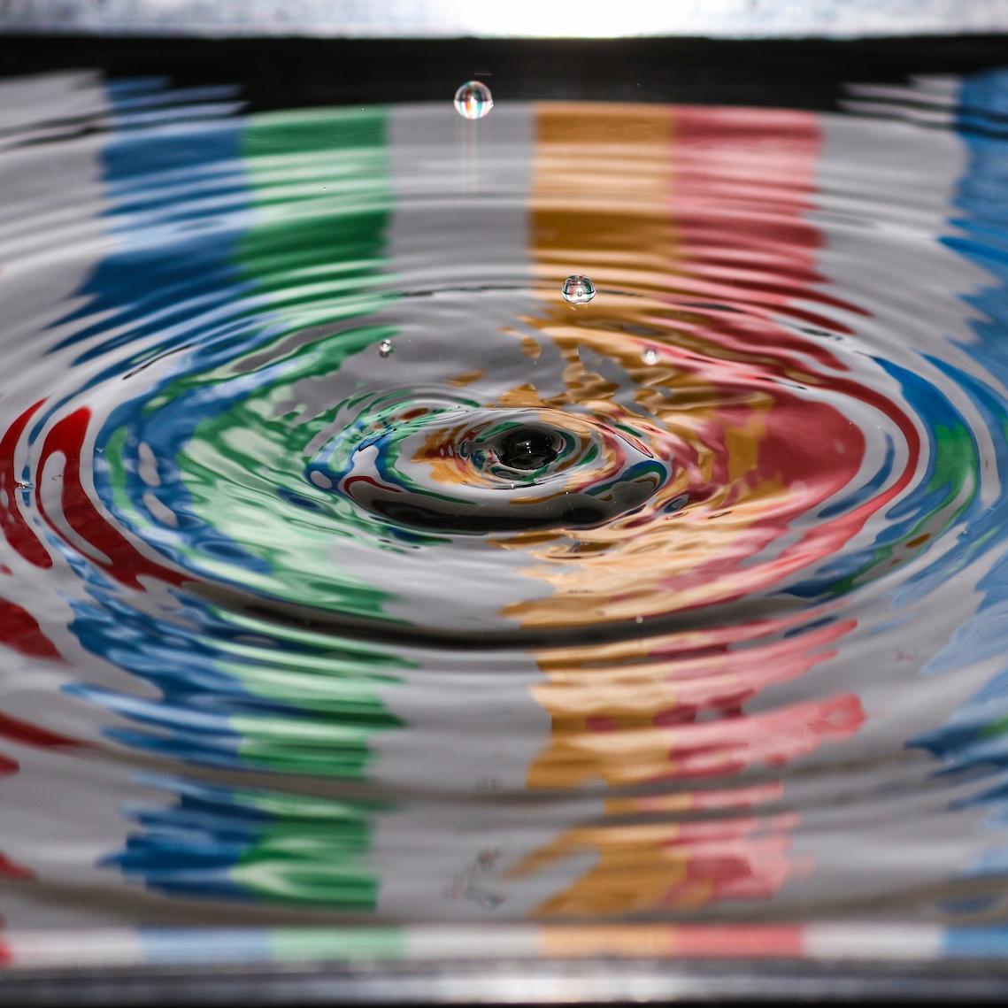 Droplet hitting water with rainbow