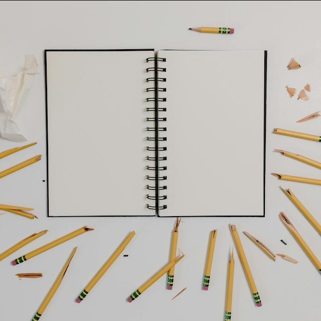 A notebook surrounded by broken pencils — failure. 