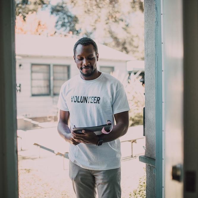 man carrying clipboard and wearing volunteer tshirt - nonprofits led by people of color