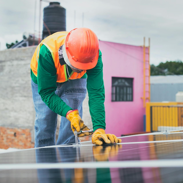 man installing solar panels on a roof