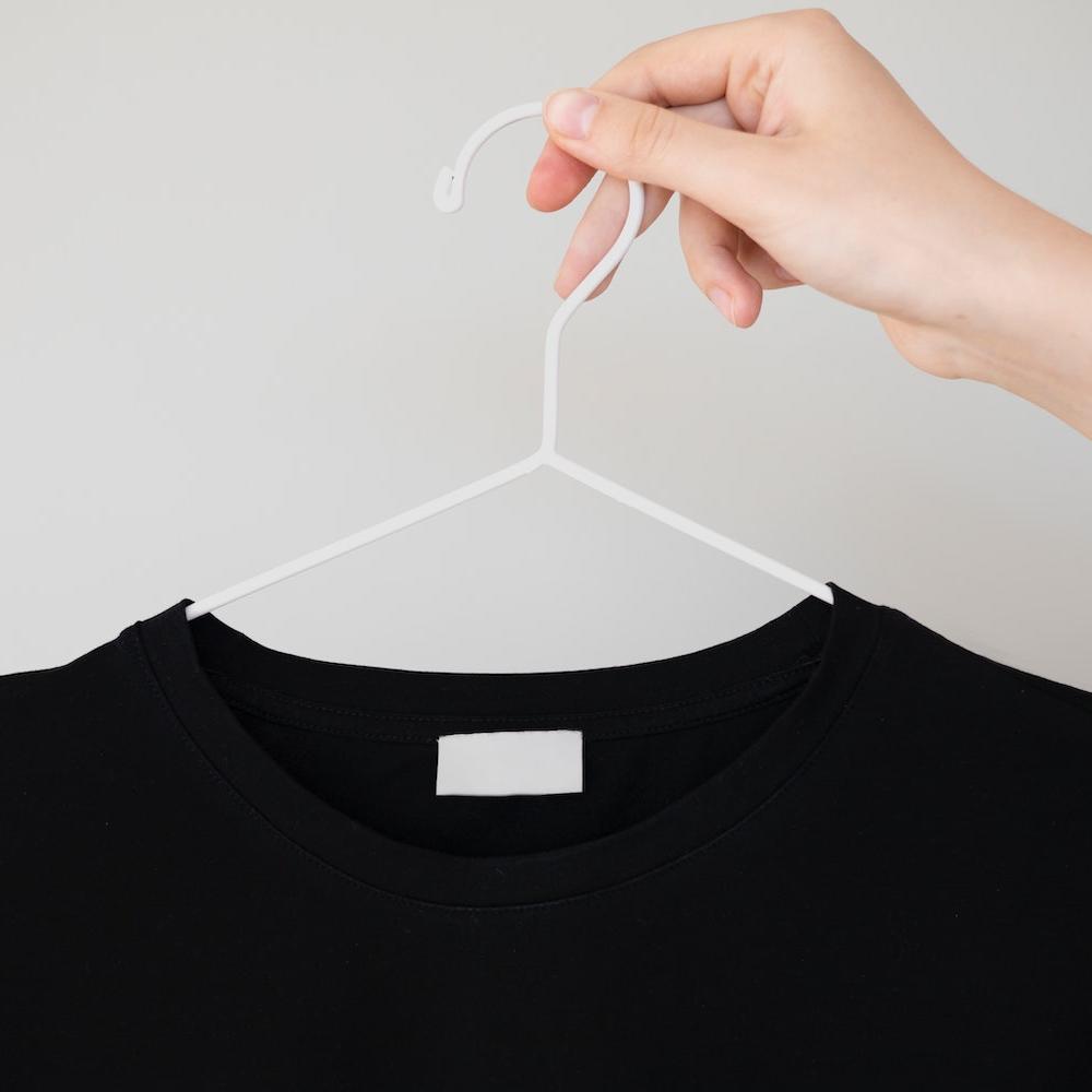 A black shirt on a hanger with a blank care label. 
