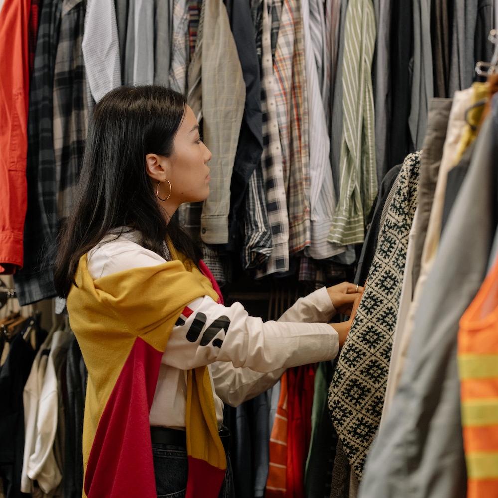 A shopper looks through clothes at a thrift store. 