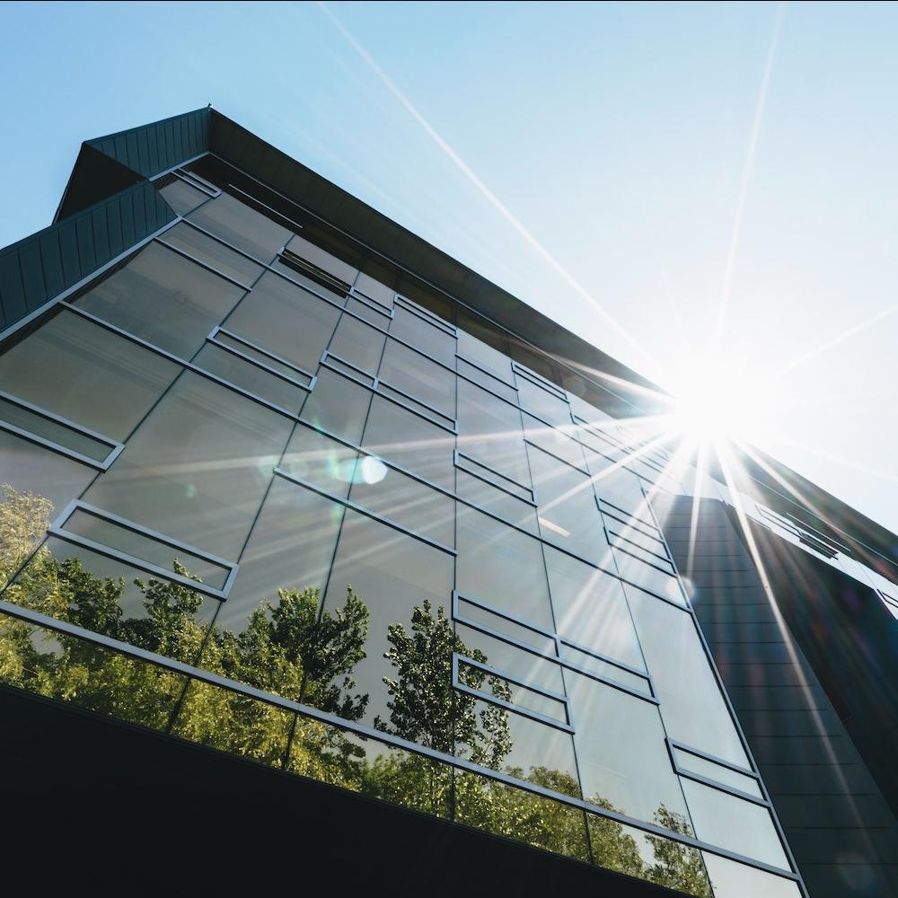 An office building with trees growing next to it. 