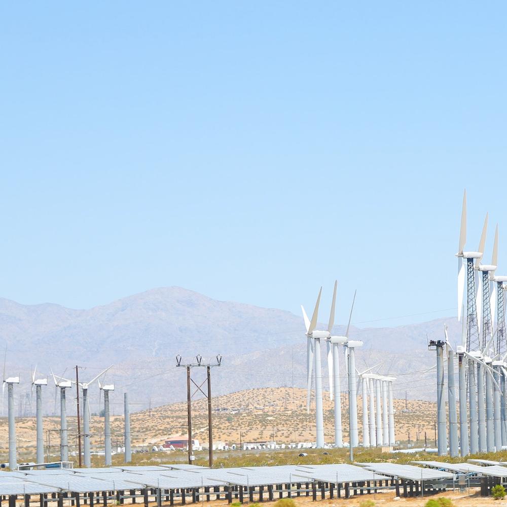 A photo showing wind turbines, solar panels and power lines  - renewable energy