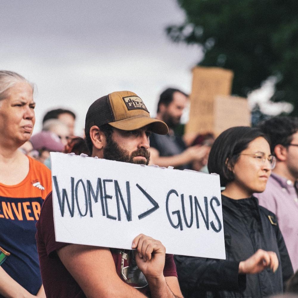 protester holds sign that reads women over guns - protesting gun violence and restrictive abortion policies