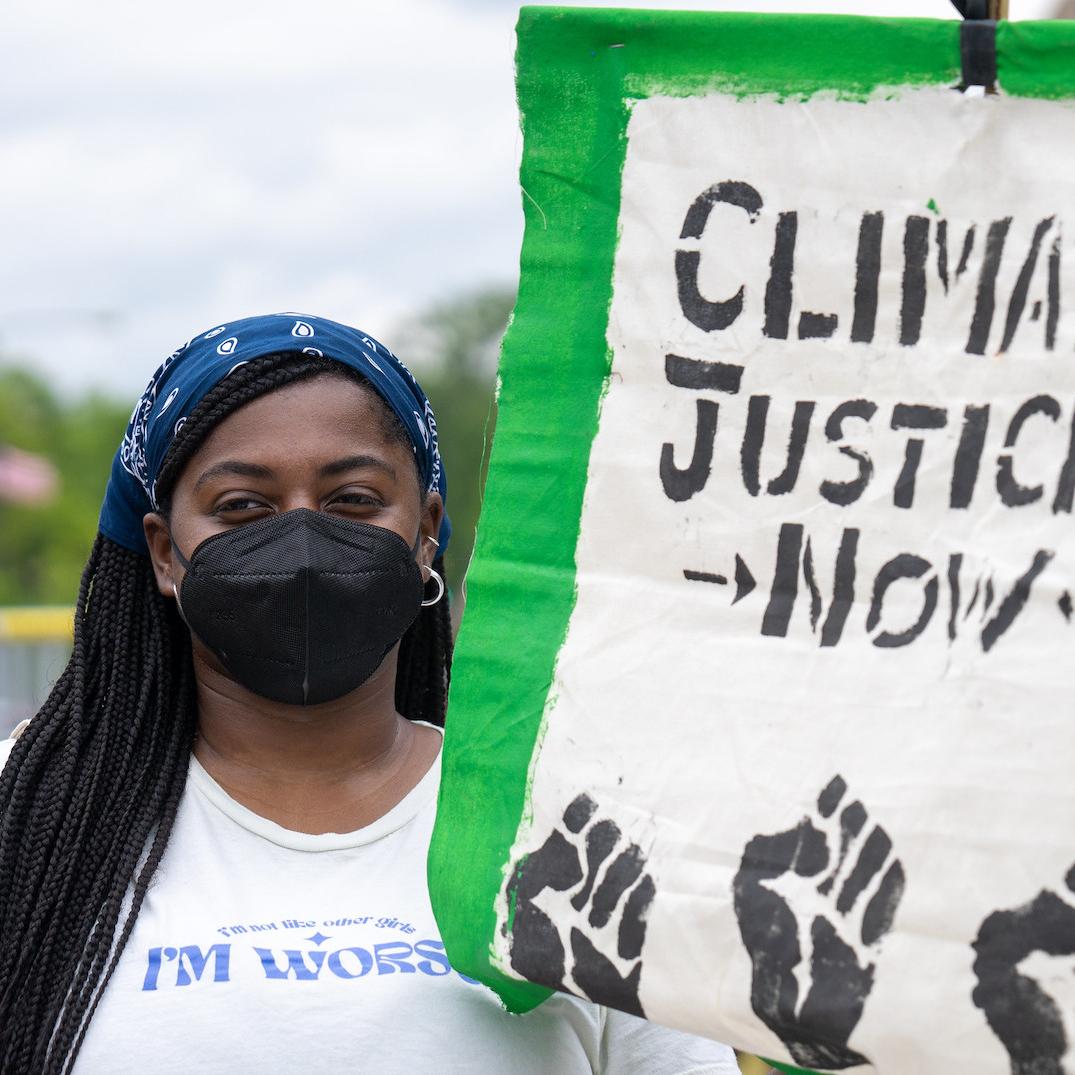 protestor holds sign reading climate justice now