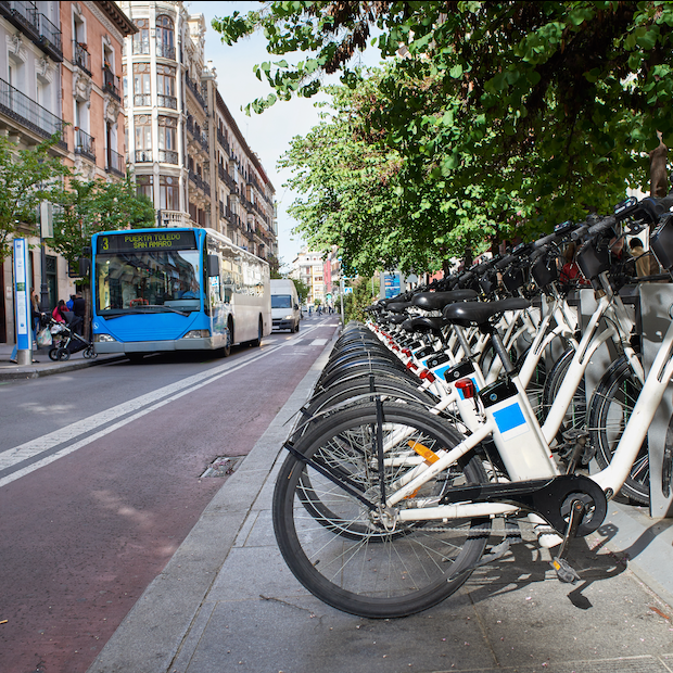 row of shared bike rentals with a bus in the background - public transportation