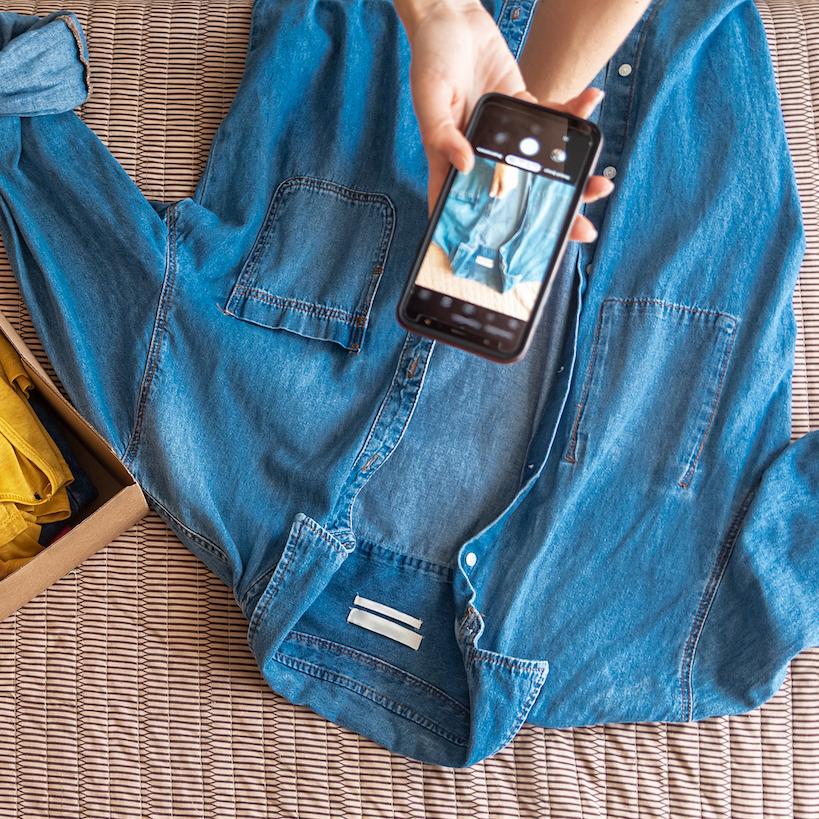 secondhand apparel - woman prepares clothes to be sold online - taking photos with her phone