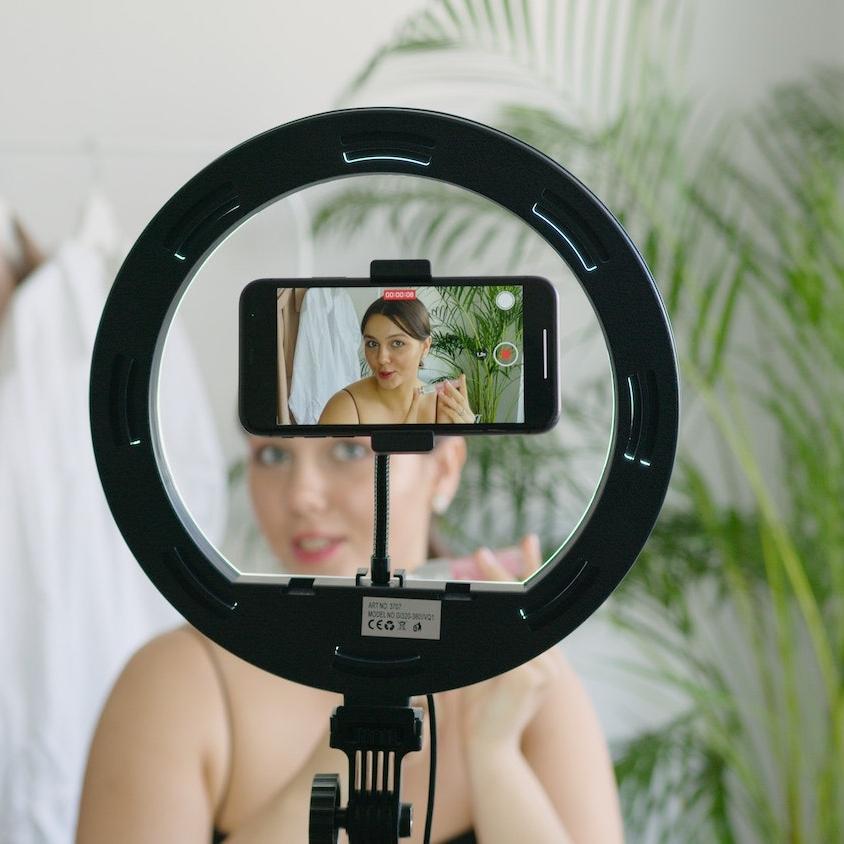 social media influencer content creator recording a video on a smartphone using a ring light - influencers can encourage sustainable consumer behavior change