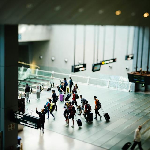 Travelers walk through an airport — sustainable travel