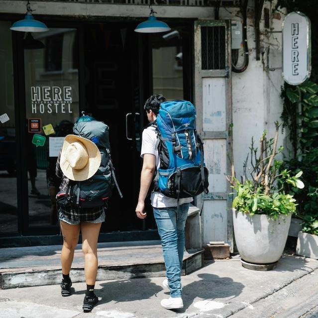 Two backpackers walking into a hostel. 
