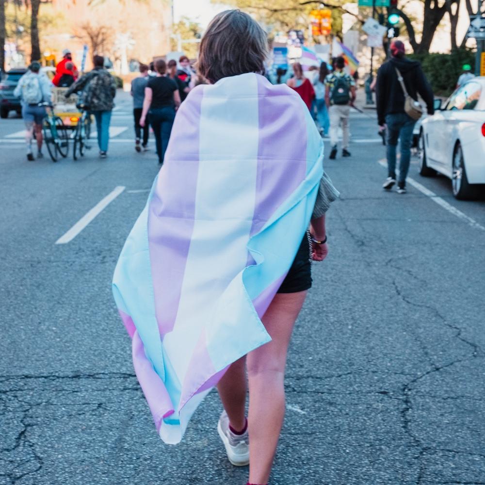 trans rights demonstrator wears trans flag