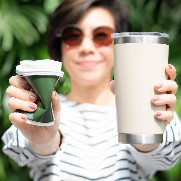 woman holding a single-use and reusable cup