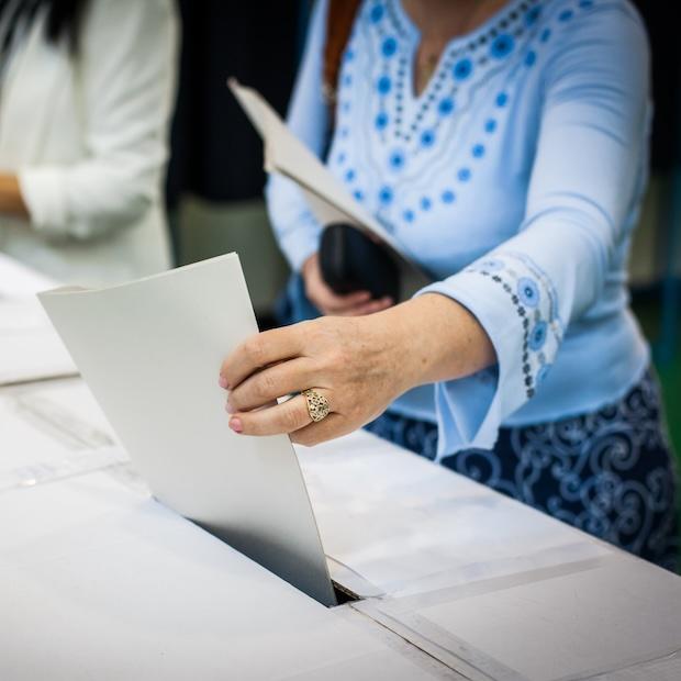 woman puts ballot in a ballot box — voting — paid time off for voting 