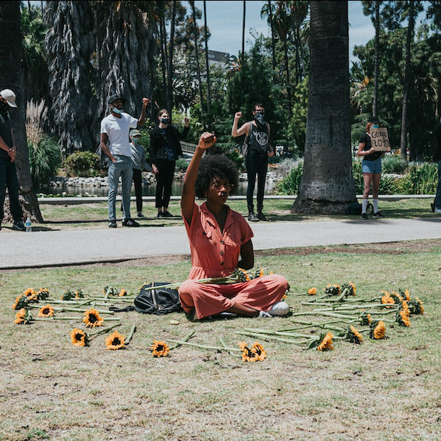 woman sitting in a circle of flowers at a social justice and civil rights demonstration in south carolina after the murder of george floyd