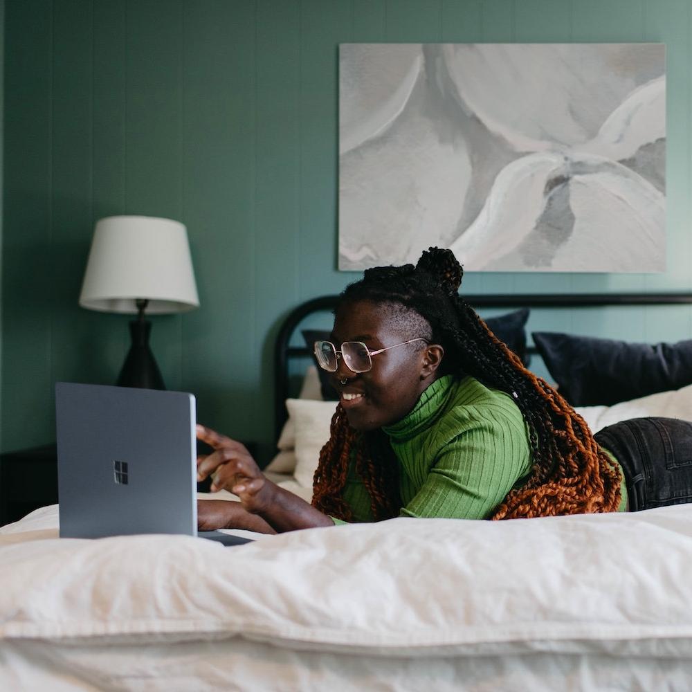 woman working from home in bed - remote work - mentoring remotely